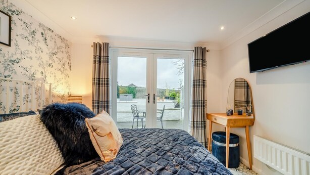 Ein Schlafzimmer mit einem Bett, einem Schreibtisch, einem Spiegel und Blick durch eine Glastür.