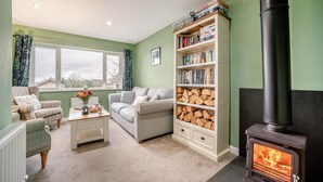 Ein gemütliches Wohnzimmer mit Kamin, Bücherregal, einer Couch und einer Heizung.