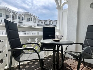 A balcony with two chairs and a table, overlooking a white building with arched windows. - Ferienwohnung im Seepark Sellin mit Balkon und Wlan (Sellin)