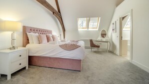 Een slaapkamer met een bed, nachtkastje, kaptafel, dressoir en een raam.