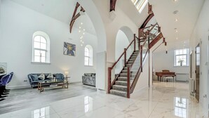A spacious living area with a grand staircase, marble flooring, and large windows. - 6 Bed in High Bonnybridge (oc-b36040) (Bonnybridge)