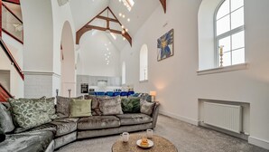 A spacious living room with a leather sofa, a coffee table, and a view of the kitchen and dining area. - 6 Bed in High Bonnybridge (oc-b36040) (Bonnybridge)