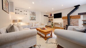 A modern living room with a fireplace, white sofas, a coffee table, and artwork on the walls. - 3 Bed in Wirksworth (oc-dchenm) (Hopton)