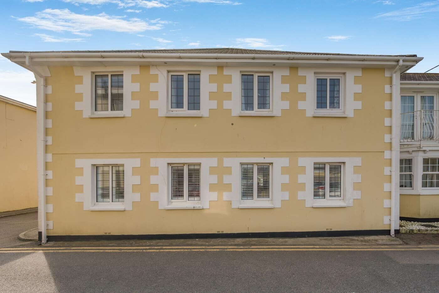 Ein zweistöckiges Gebäude mit gelber Fassade und weißen Fensterrahmen.
