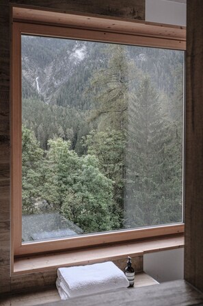 Een uitzicht op een bebost berggebied vanuit een raam.