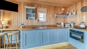 Une cuisine avec des murs en bois, une cuisinière encastrée, un évier et des tabourets de bar.