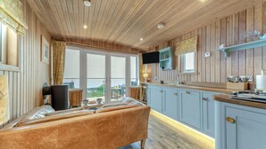 A room with a bed, a TV, a kitchen area, and a large window. - 1 Bed in Gatehouse Of Fleet (oc-d34894) (Gatehouse of Fleet)