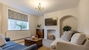 Een woonkamer met een open haard, een televisie en twee banken.