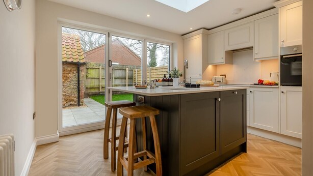 Een moderne keuken met een groot keukenblok, barkrukken en een dakraam.