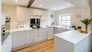 A modern kitchen with white cabinetry, a built-in oven, a sink, and a breakfast bar. - 2 Bed in Haxby (oc-t36047) (Haxby)