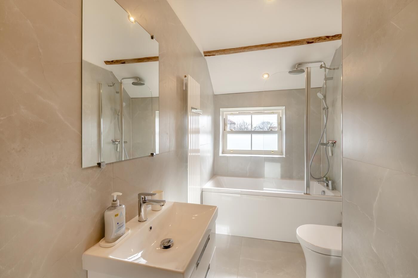 A modern bathroom with a vanity, a shower, and a window.