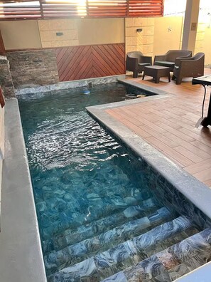 Ein Schwimmbecken mit Holzterrasse und Steinwänden.