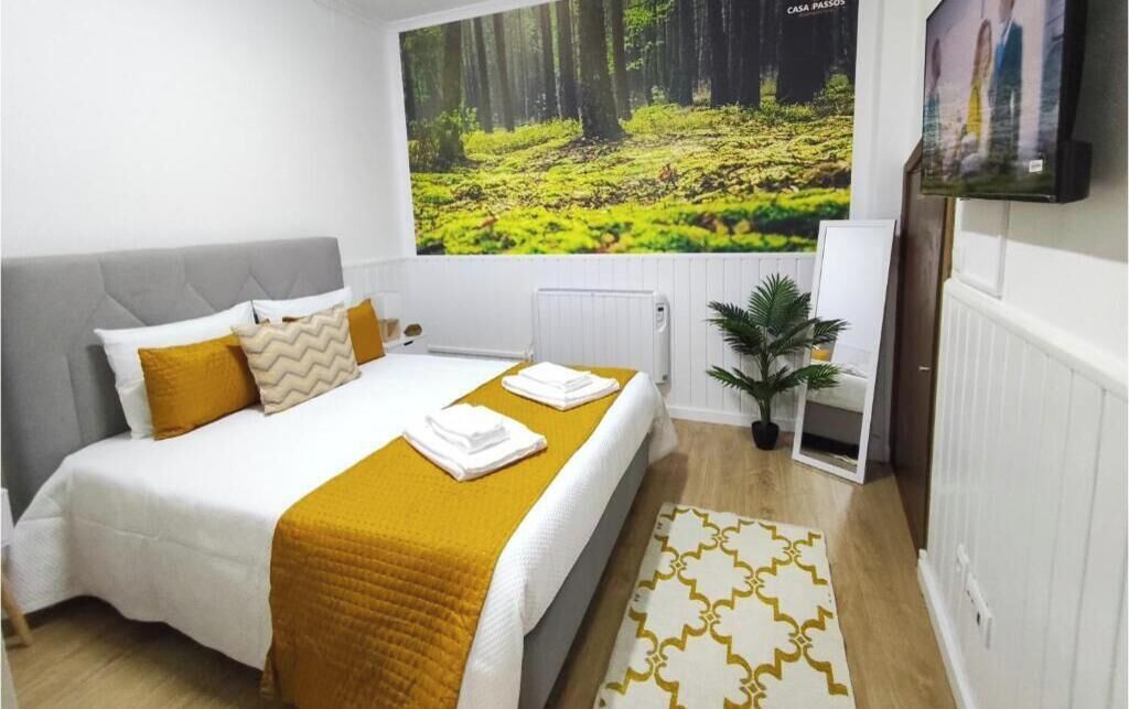 Une chambre à coucher avec un lit, une grande fresque murale sur le thème de la forêt, un radiateur, une plante en pot et un tapis à motifs.
