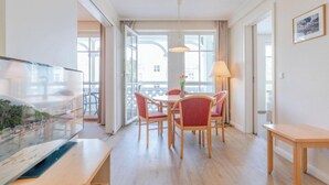 A hotel room with a dining area, a large window, a flat-screen TV, and a lamp. - Auszeit auf Rugen Nahe Ostsee (Sellin)