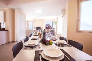 A dining area with a long table set for a meal, chairs, and a view of the outside. - Villa Donagh sleeps 12, lake view & pool by Italian Apartments. (Ossuccio)