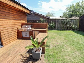 A wooden deck with a built-in grill and a potted plant. - 80 Pentney Lakes (King's Lynn)