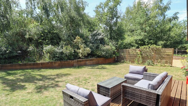 Une terrasse extérieure avec des meubles en osier et une plateforme en bois.