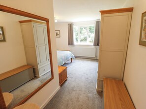 A bedroom with a bed, a wardrobe, a mirror, a radiator, and a window with curtains. - 80 Pentney Lakes (King's Lynn)