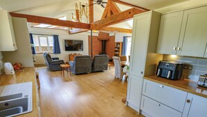 Un vaste espace de vie comprenant une cuisine, un plancher en bois et un coin repas avec une table et des chaises.