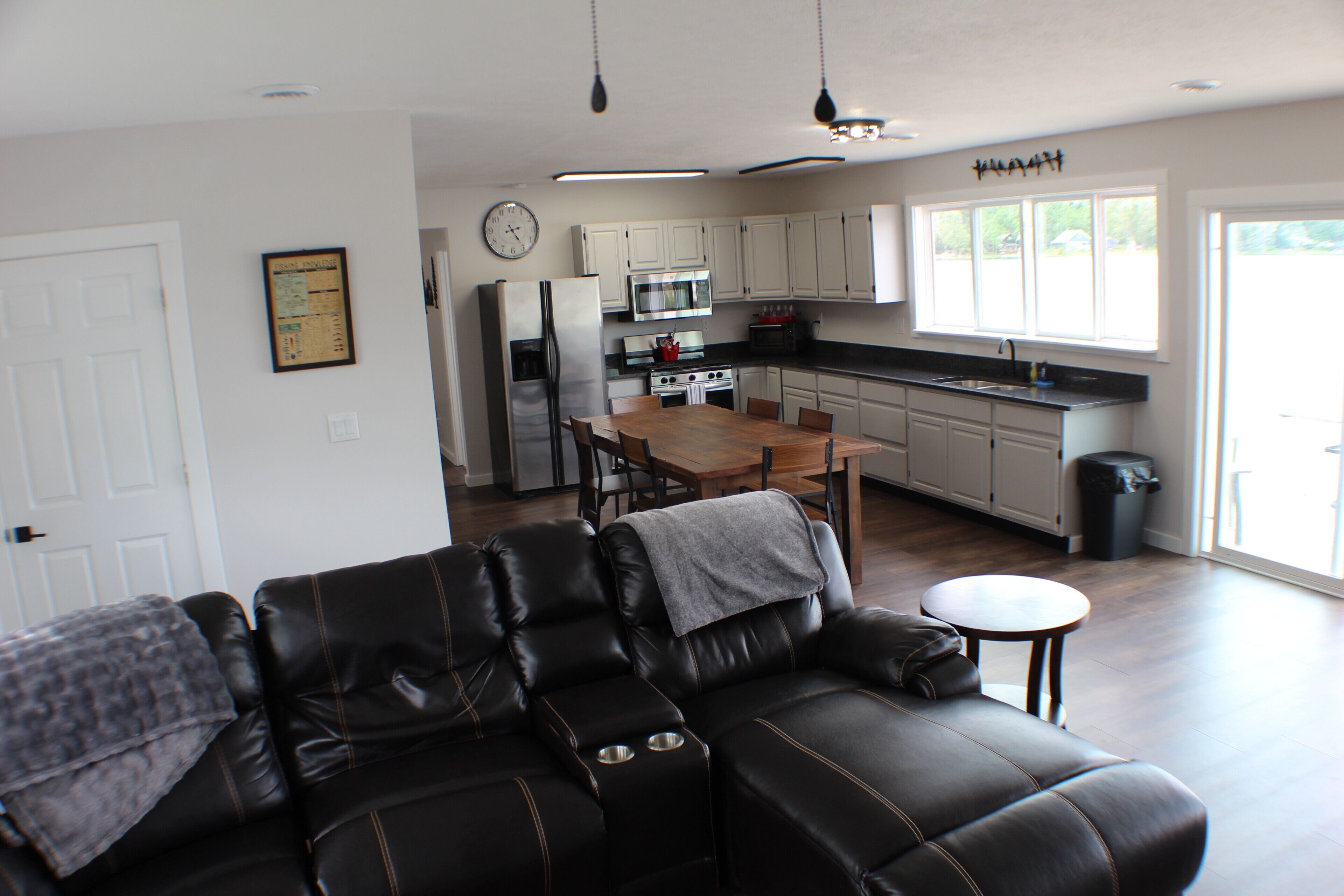 A living room with a leather sofa, a dining table, and a kitchen in the background.