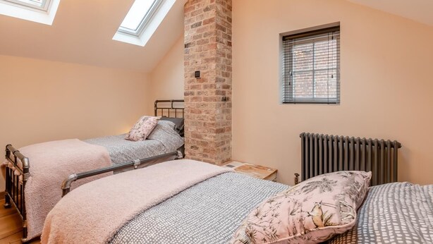 A bedroom with two beds, a brick wall, a radiator, and skylights. - 2 Bed in Belchford (oc-o36036) (Belchford)