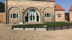 A stone building with a red-tiled roof, arched windows, and a small lawn area. - 2 Bed in Belchford (oc-o36036) (Belchford)