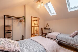 Ein Schlafzimmer mit zwei Betten, einem Kleiderschrank, einem Schreibtisch und einem Oberlicht.