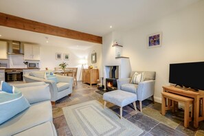 Ein modernes Wohnzimmer mit Kamin, Fernseher und Essbereich.