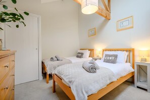 Ein Schlafzimmer mit zwei Betten, einer Holzkommode und einer Deckenleuchte.