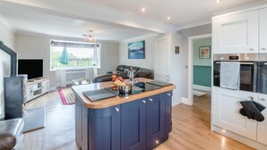 Una cocina moderna con una isla central, horno empotrado y un rincón comedor con sofá y mesa.