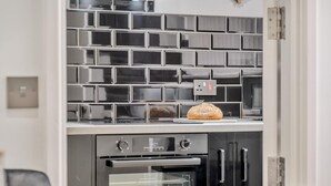 Eine Küche mit gefliestem Fliesenspiegel, einem Backofen und einem Brot auf der Arbeitsfläche.