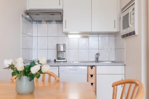 Eine Küche mit weißen Schränken, einer Edelstahl-Dunstabzugshaube, einer Mikrowelle und einer Kaffeemaschine.