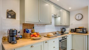 A modern kitchen with light-colored cabinets, a coffee maker, a toaster, and a bowl of fruit. - 2 Bed in Snettisham (oc-k36331) (Snettisham)
