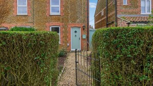 A residential building with a stone facade, a green door, and a small window. - 2 Bed in Snettisham (oc-k36331) (Snettisham)