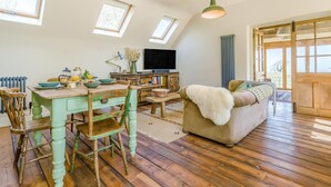 A loft-style room with a dining area, a sofa, a television, and a view of the outdoors. - 1 Bed in Picklescott (oc-o35147) (Ratlinghope)