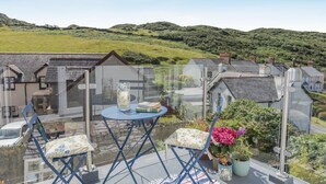 A balcony with a table, chairs, and potted plants. - 4 Bed in Mortehoe (oc-d35057) (Mortehoe)
