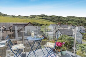 A balcony with a table, chairs, and potted plants. - 4 Bed in Mortehoe (oc-d35057) (Mortehoe)