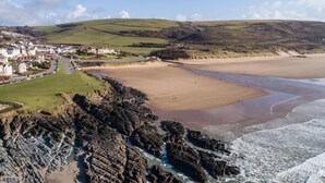 A coastal town with a sandy beach, rocky coastline, and a residential area with houses. - 4 Bed in Mortehoe (oc-d35057) (Mortehoe)