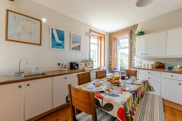 Una cocina con una mesa de comedor, sillas, una cafetera y un mapa en la pared.