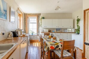 A kitchen with wooden cabinets, a dining table with a polka dot tablecloth, and a view through a window.