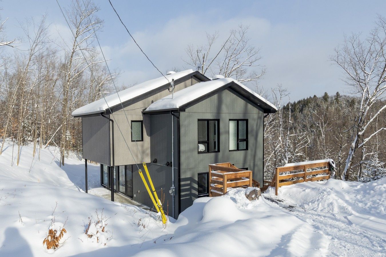 A modern cabin with a sloped roof, large windows, and a wooden deck.