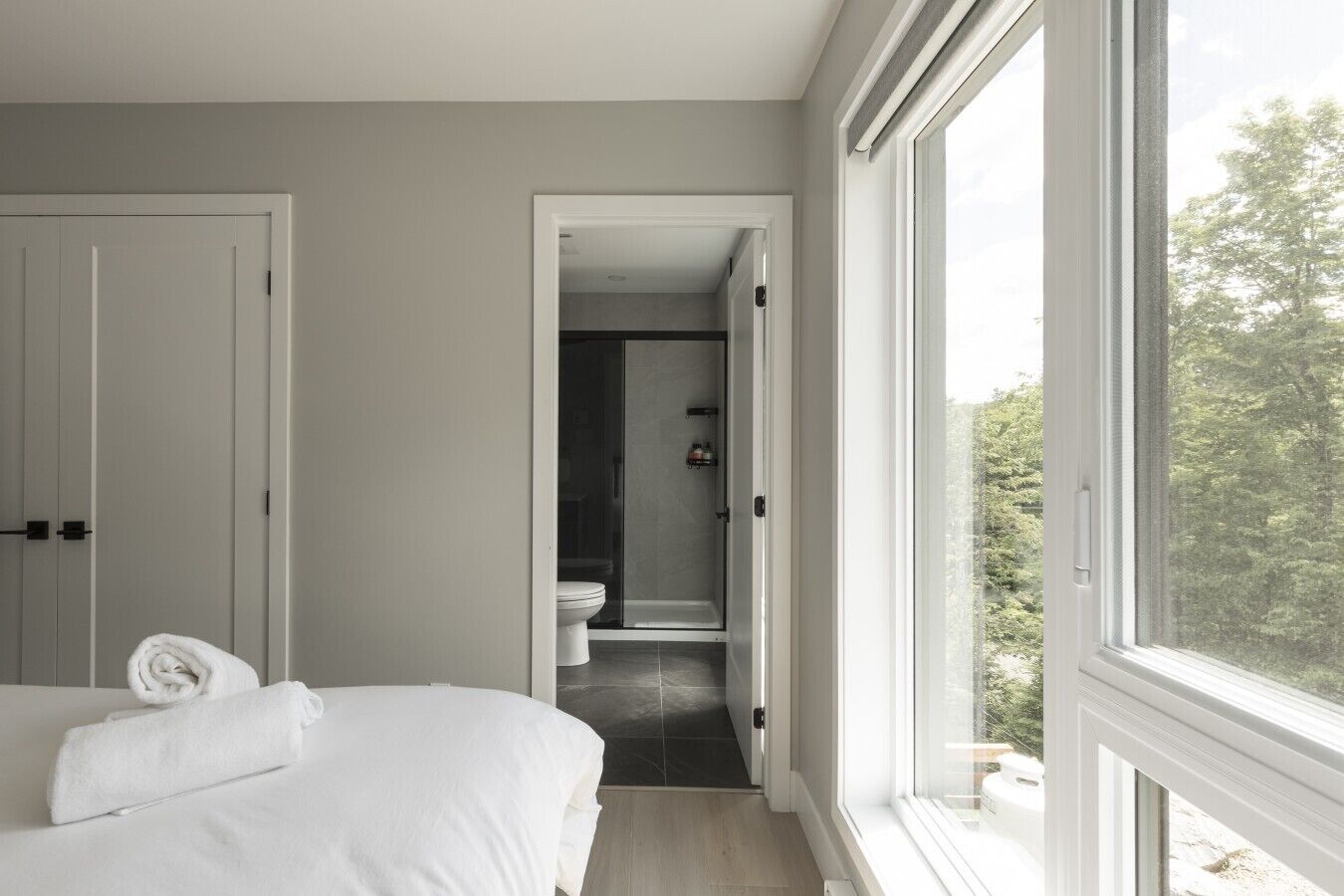 Een slaapkamer met een bed, een badkamer met toilet en douche, en uitzicht door een raam.