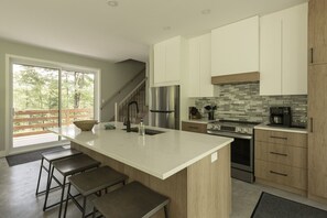 Een moderne keuken met een groot eiland, roestvrijstalen apparatuur en uitzicht op het buiten.