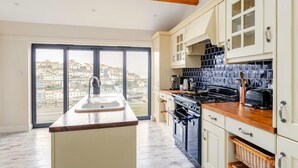 A kitchen with a large window, a sink, a stove, and cabinets. - 4 Bed in Brixham (oc-t35056) (Brixham)