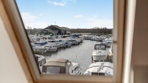 Puerto deportivo con barcos amarrados, un edificio al fondo y cielo despejado.