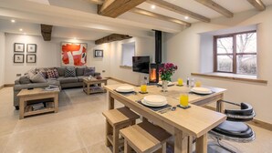 Ein moderner Wohnraum mit Essbereich, Sofa, Fernseher, Kamin und Kunstwerken.