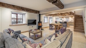 Ein modernes Wohnzimmer mit einer Couch, einem Fernseher, einem Kamin und einer Treppe, die zur Küche hinaufführt.