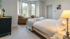 Une chambre avec un grand lit, une chaise, un bureau et une fenêtre.