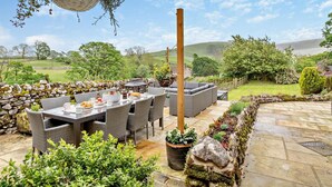 An outdoor patio with wicker furniture, a stone wall, and a hanging basket. - 4 Bed in Skipton (oc-95155) (Thorpe)