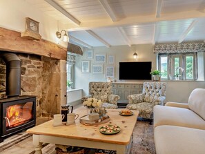 Ein gemütliches Wohnzimmer mit Kamin aus Stein, bequemen Sitzgelegenheiten, einem Flachbildfernseher und gerahmten Bildern an den Wänden.